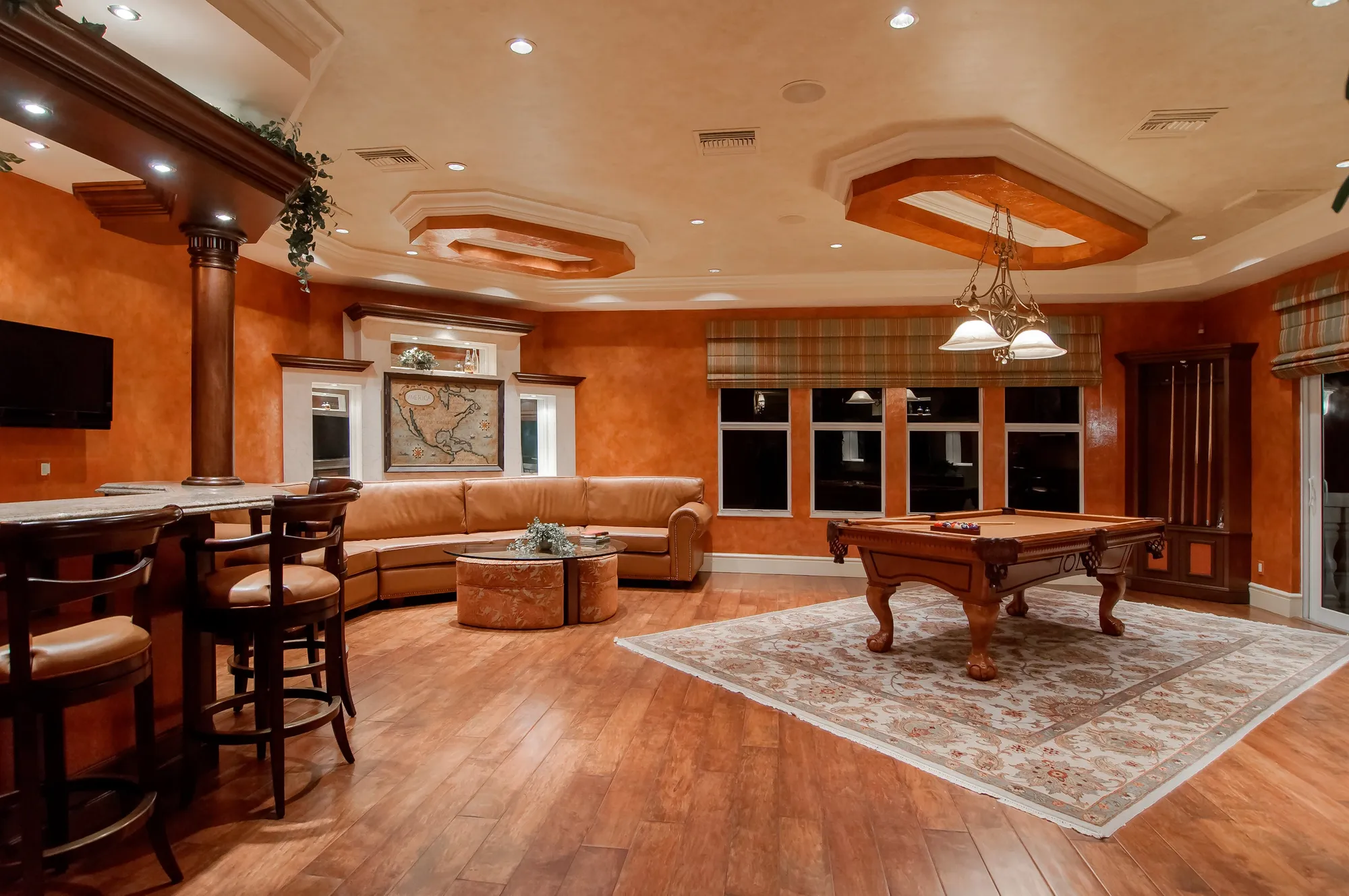 Tall arched windows on either side of a fireplace in a wood-floored living room